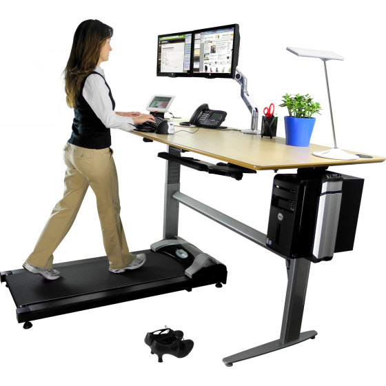 Woman working at desk while using treadmill