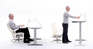 photo of man sitting at desk then standing at raised desk